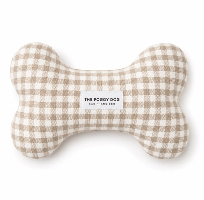 A bone-shaped dog toy made of beige and white gingham fabric, featuring a white label in the center that reads 'THE FOGGY DOG SAN FRANCISCO'.