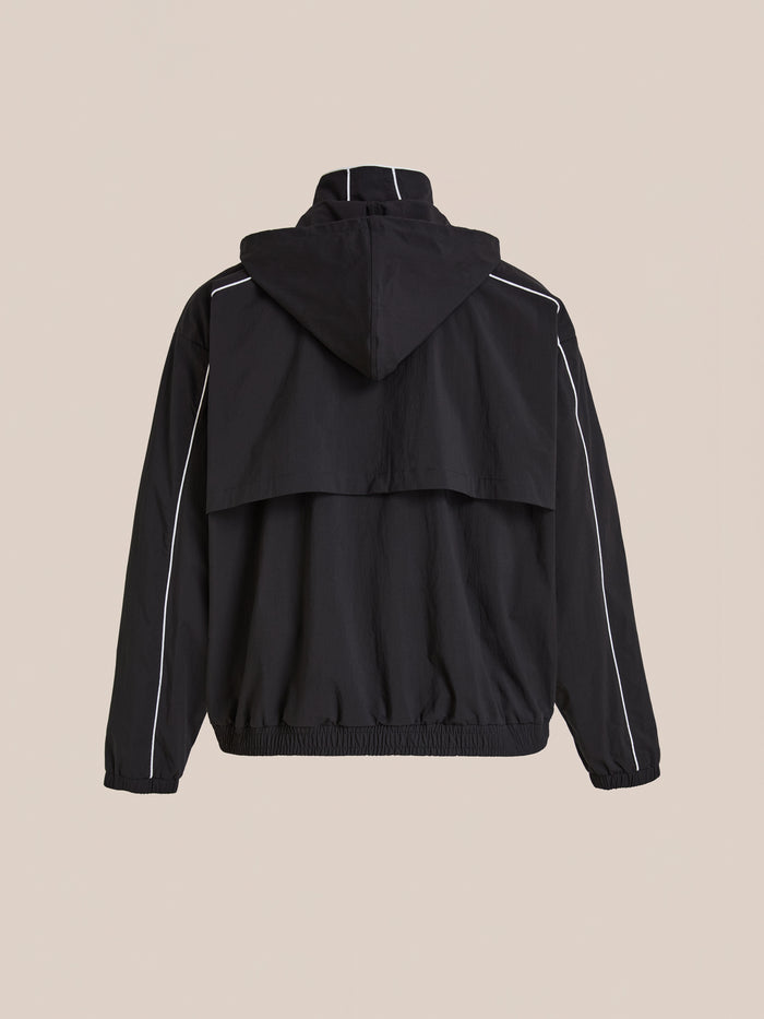 The FOUND Arena Stripe Track Jacket is a unisex black track jacket with white piping, made from lightweight technical fabric, shown from the back on a plain beige background.