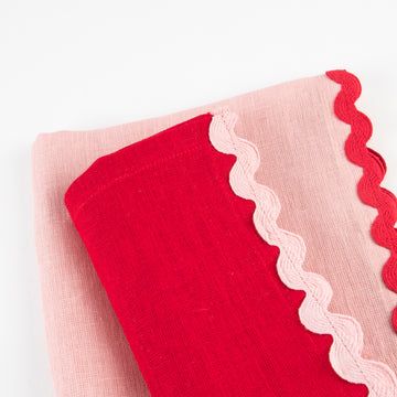 Red and pink fabric with scalloped edge on a white background