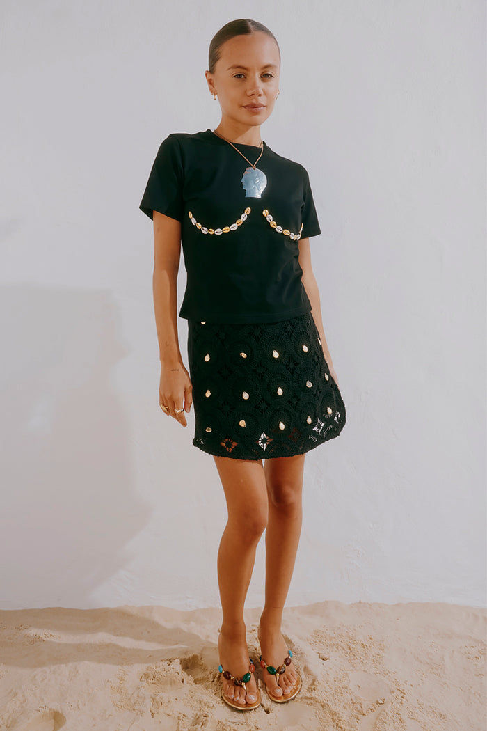 Black Crochet Shell Wrap Skirt with gold shell embellishments, styled with a black shell tee for a vacation look.