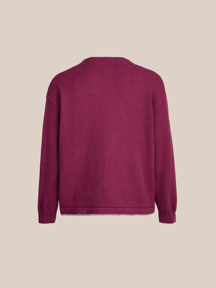 Back view of the FOUND Double Breasted Bow Cardigan, a unisex relaxed fit long-sleeve dark pink knit sweater with ribbed cuffs and a plain design, shown on a beige background.