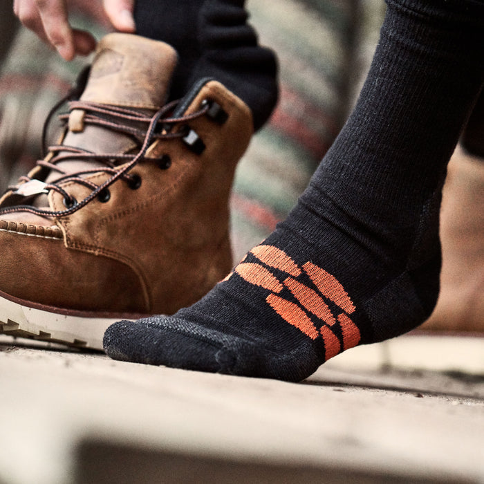 View 2 man putting on high quality, durable performance socks with BRUNT logo in black * 1