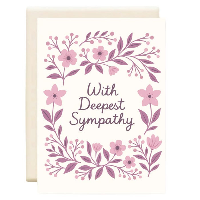 A sympathy greeting card with an off-white background, featuring a floral border in shades of pink and mauve with the words 'With Deepest Sympathy' in dark mauve script. A matching off-white envelope is partially visible behind the card.