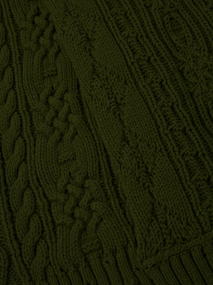 Close-up of the Forest Distressed Cable Knit Scarf by FOUND, showcasing its green fabric with various intricate cable patterns and textures.