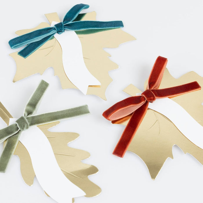 Decorative paper cutouts of trees with colorful velvet ribbons on a white background