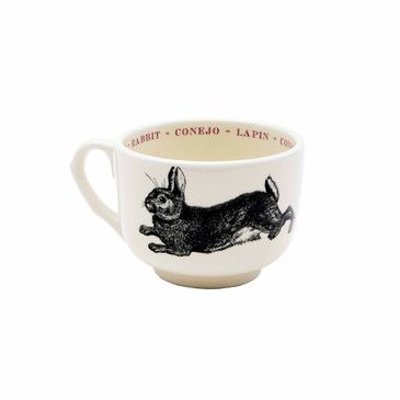 Ceramic mug with rabbit illustration and text on a white background