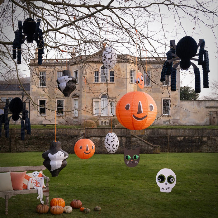 Halloween decorations including pumpkins, ghosts, and spiders in front of a large building.