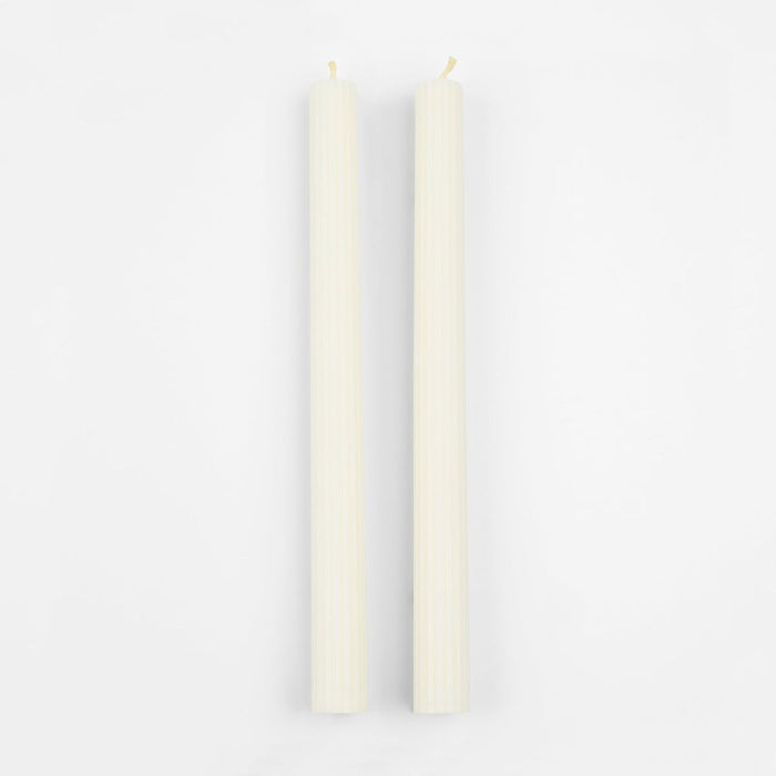 Two white candles on a light gray background