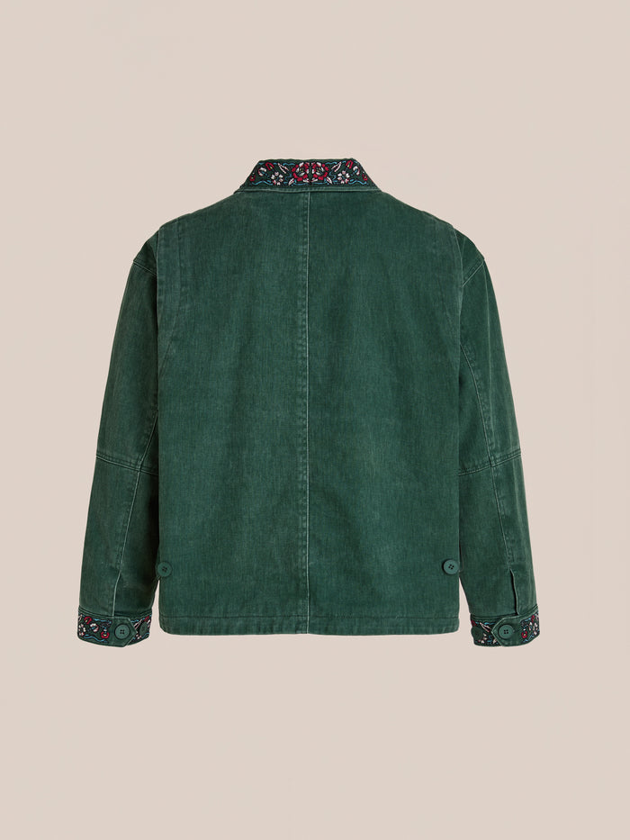 Back view of the Found Jockey Club Embroidered Jacket in green denim, unisex relaxed fit, with racing horses embroidery on collar and cuffs, shown against a plain beige background.