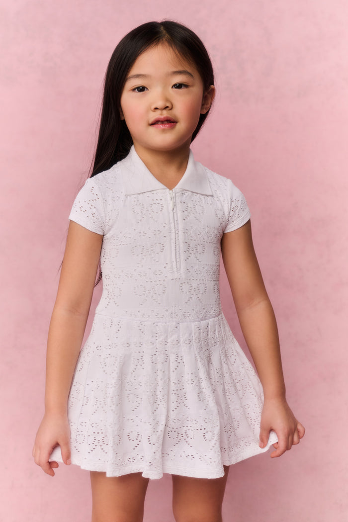 Young girl wearing a white t-shirt dress against a pink background