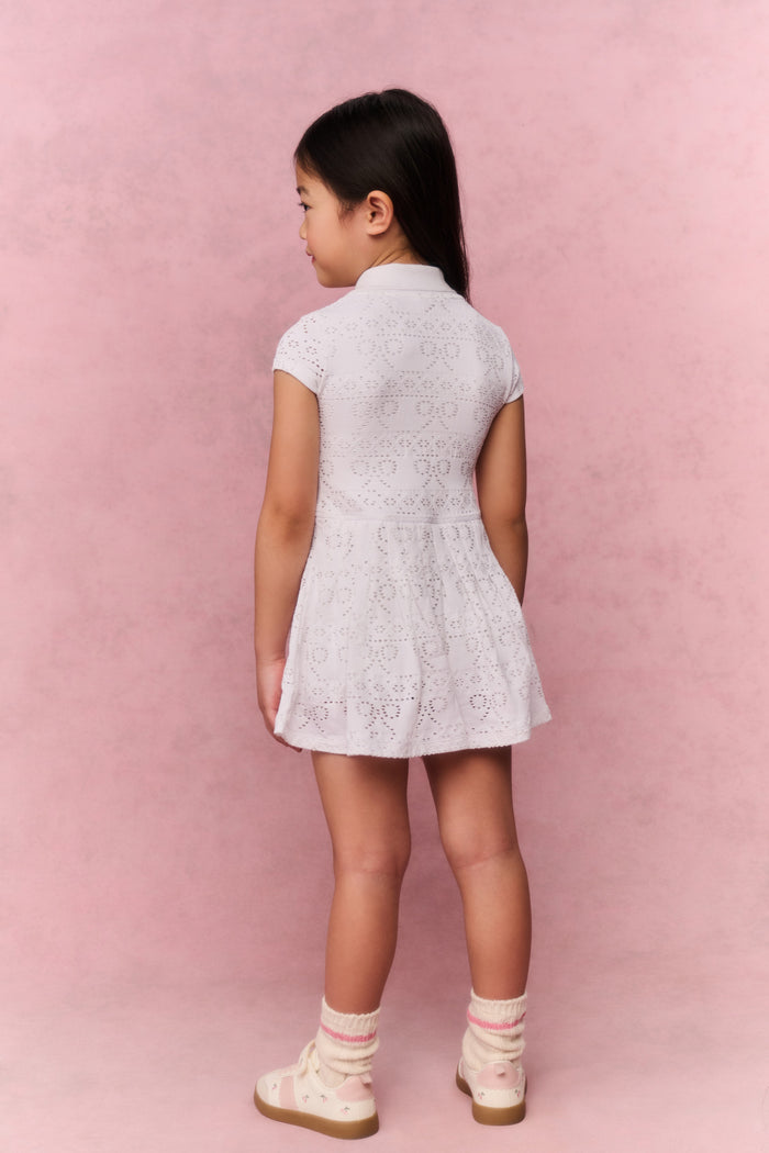 Young girl wearing a white t-shirt dress against a pink background