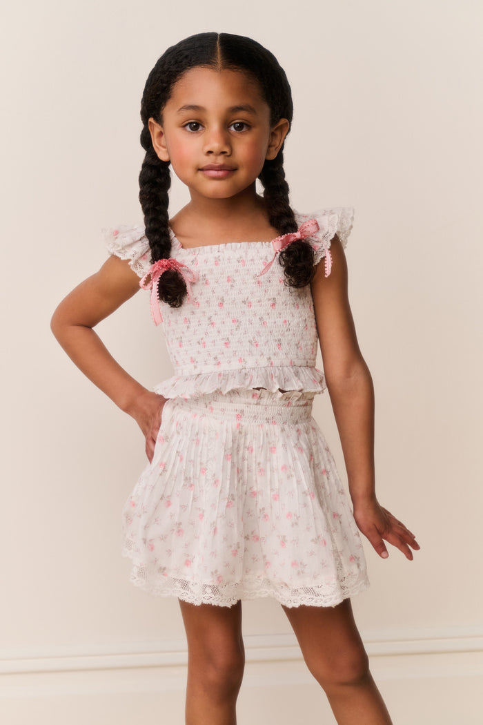 Young girl wearing a Light pink lace floral skirt and top with pink floral patterns on a plain background