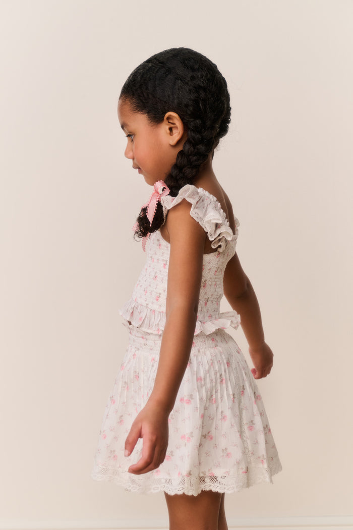 Young girl wearing a Light pink lace floral skirt and top with pink floral patterns on a plain background