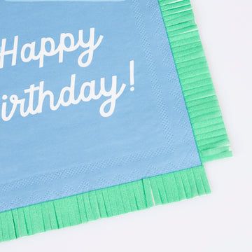 Blue napkin with 'Happy Birthday!' text and green trim on a white background