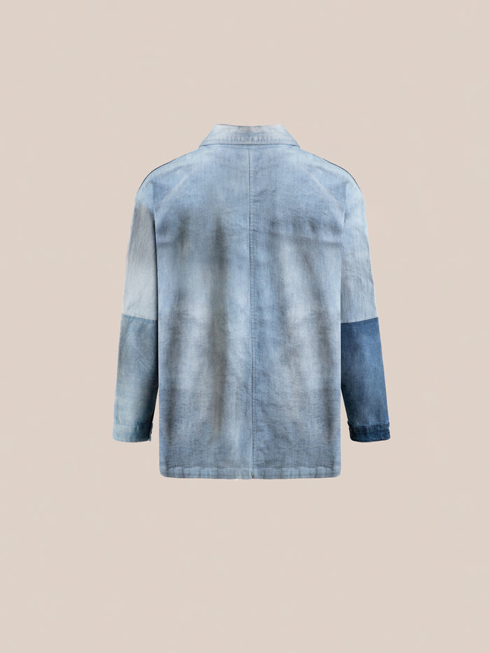FOUND's Multi Patch Painters Work Jacket is showcased against a neutral background, displaying a light blue denim design with a dark blue patch on the right sleeve and unique hand distressing for added character.