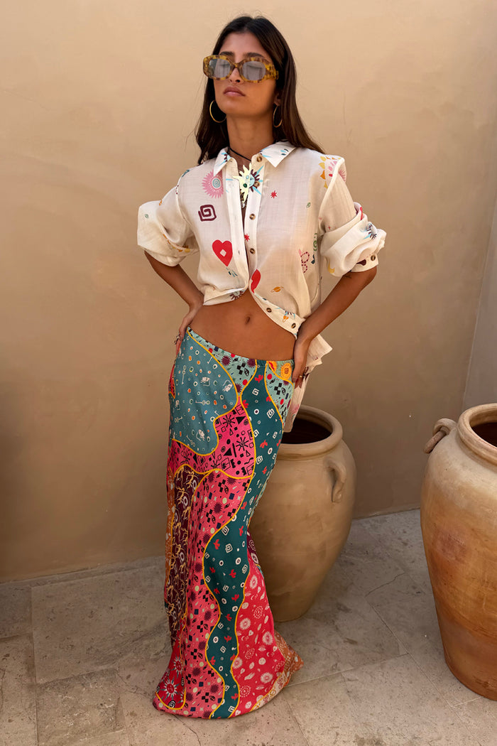 Pastel Morocco Dorris Skirt with multi-colour sun and snake motifs, shown on a model next to terracotta jars.