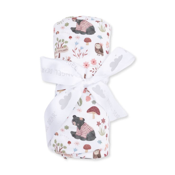 A rolled baby blanket or swaddle with a woodland bear print, tied with a white ribbon, on a plain white background.