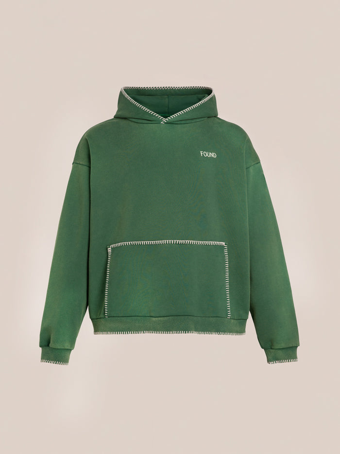 The Stitched Border Distressed Logo Hoodie by FOUND features soft French terry cotton, white contrast stitching, a front kangaroo pocket, and a "FOUND" print on the left chest. Shown here in an oversized vintage fit against a plain background.