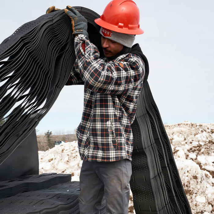 Man on jobsite wearing the BRUNT quilted flannel work jacket in black white plaid