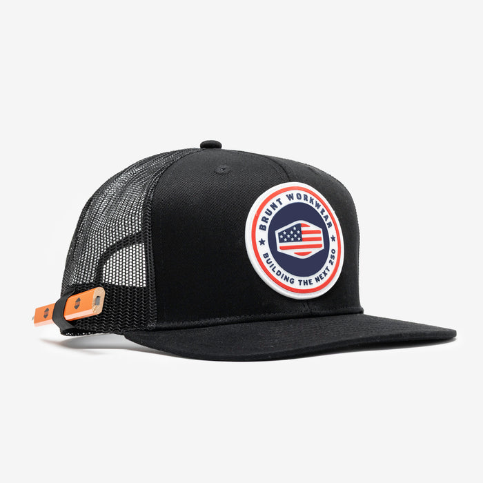 45 degree angle of front of flat brim work hat with built in pencil holder and BRUNT usa 250 logo in limited edition black