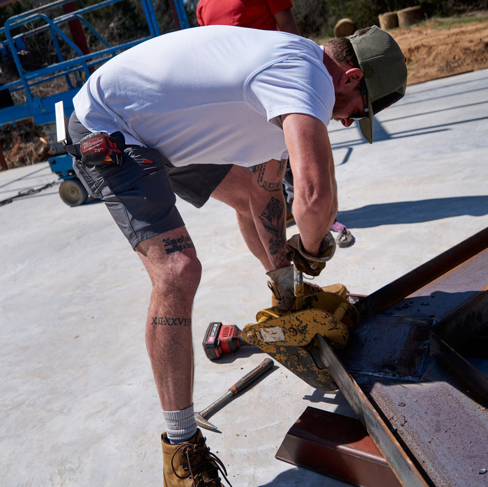 Man on jobsite wearing BRUNT 9 inch lightweight breathable costello work shorts in charcoal