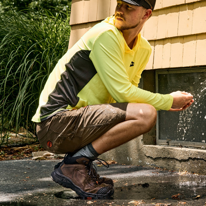 Man on jobsite wearing BRUNT lightweight mckenna sun hoodie with UPF protection in safety yellow