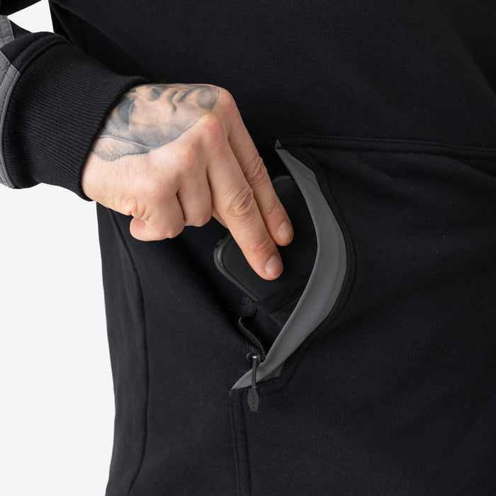 Front of hand pocket with man putting phone in tech pocket of the BRUNT water resistant heavy duty shevlin work hoodie in black/charcoal