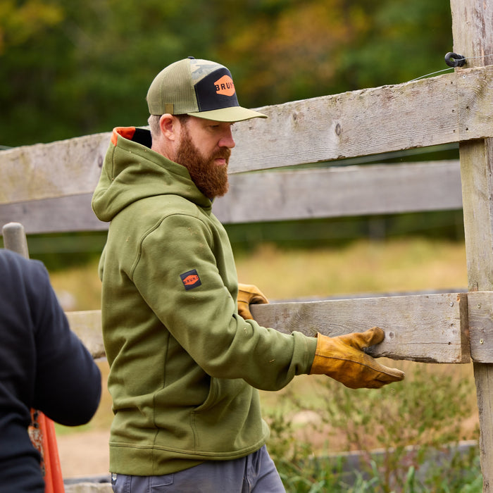 Man on jobsite wearing the BRUNT water resistant shevlin work hoodie in hunter green