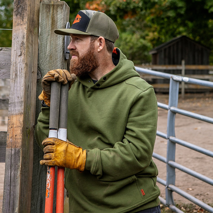 Man on jobsite wearing the BRUNT water resistant shevlin work hoodie in hunter green
