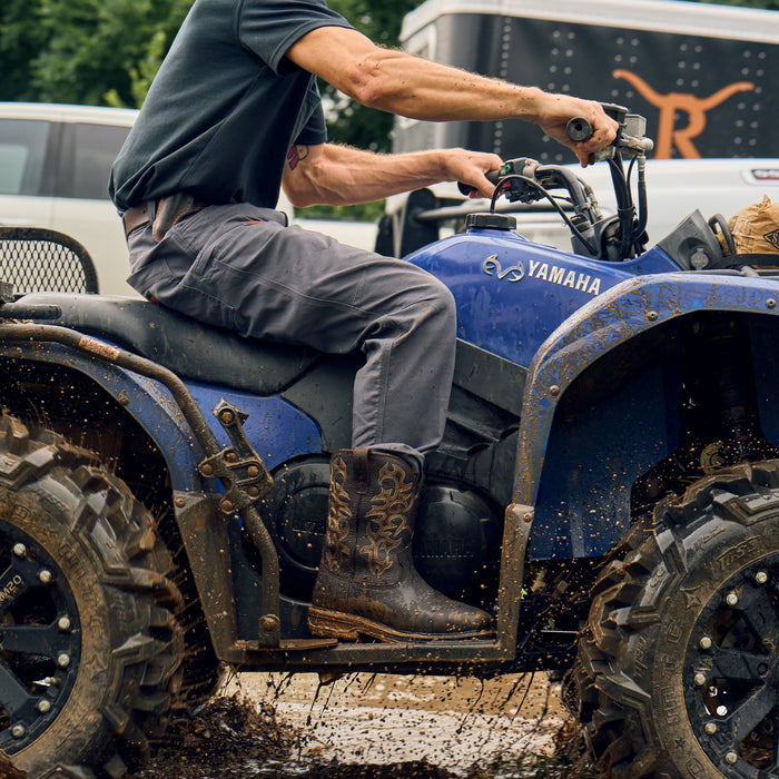 Man wearing BRUNT 10 inch welted waterproof composite square toe work boot in dark brown riding four wheeler