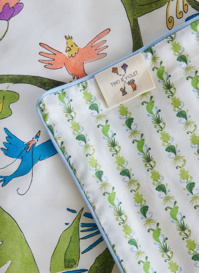 Children's fabric with colorful bird and leaf pattern, featuring a brand tag.