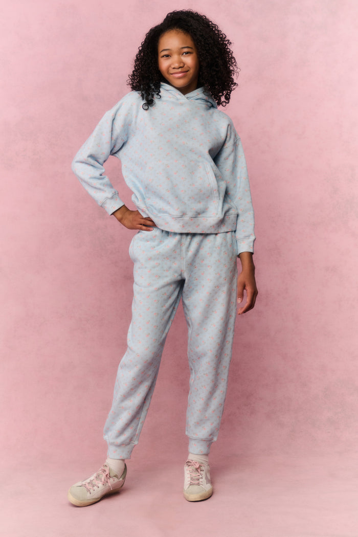 Young girl wearing a blue sweatshirt and pants on a pink background