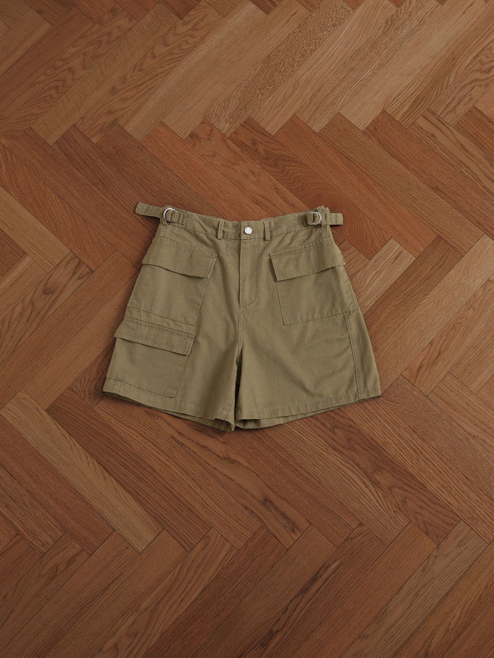 A pair of Found Twill Cargo Shorts with cargo pockets on a wooden floor.